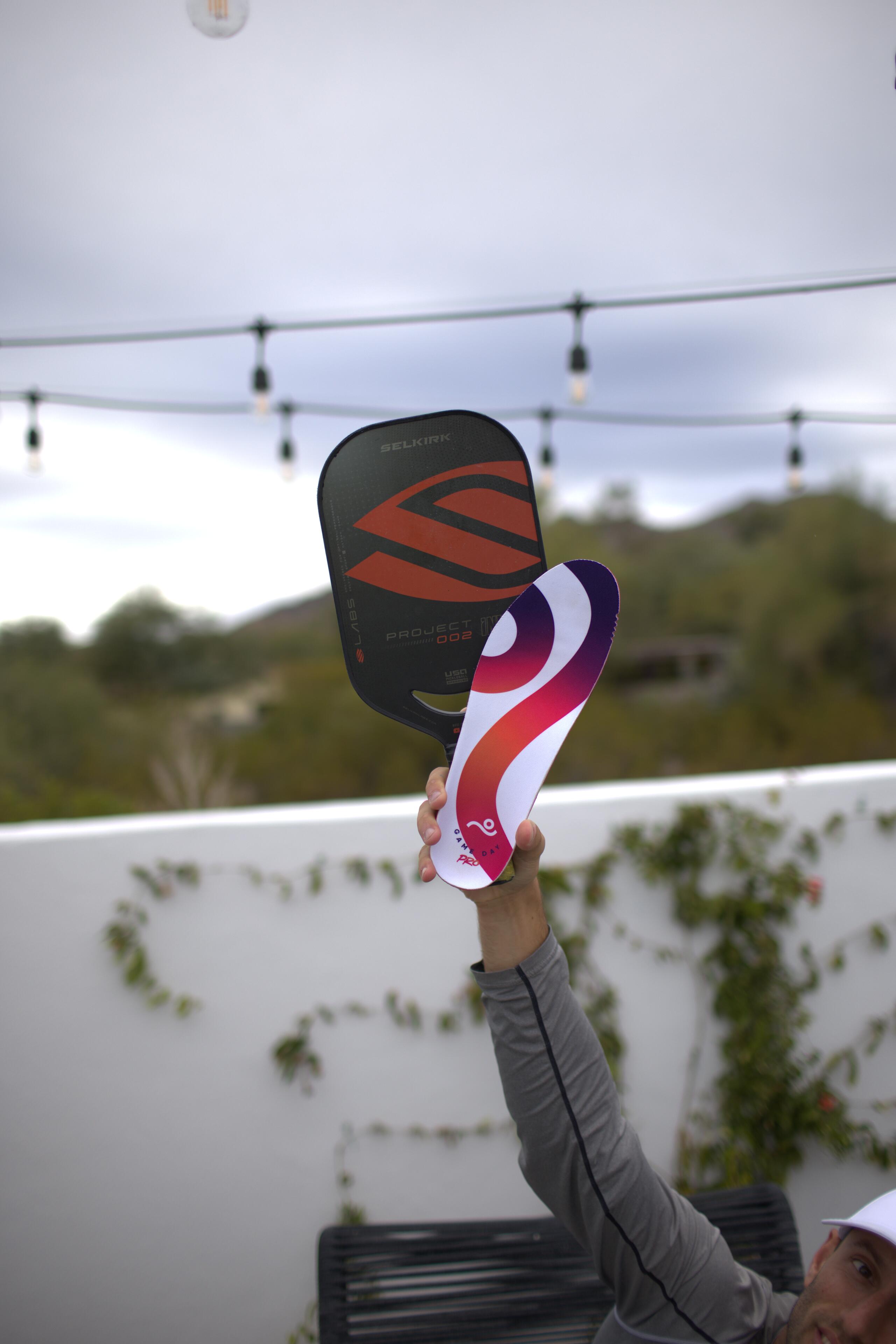 Kyle Koszuta with two paddles under string lights