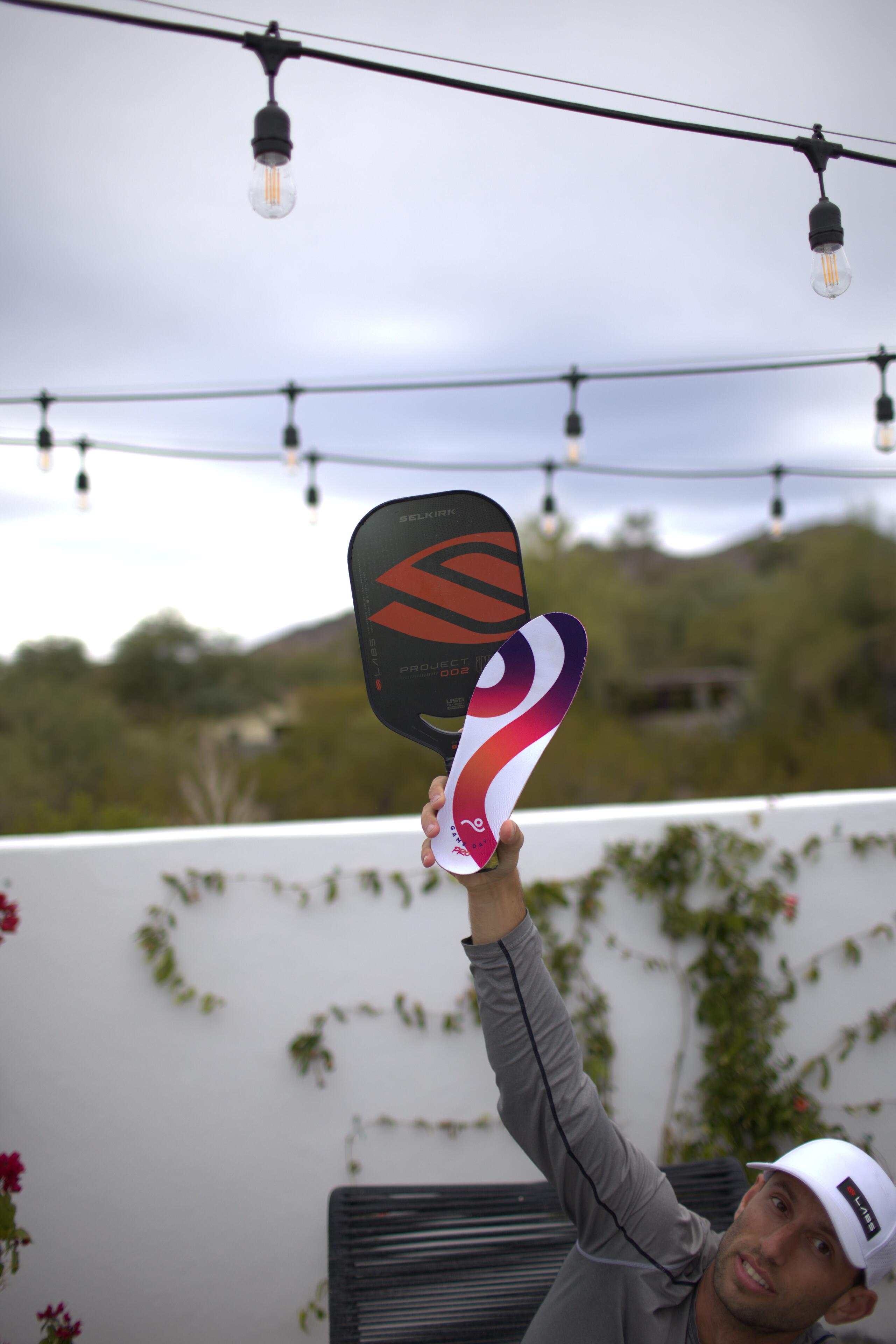 Kyle Koszuta holding two Selkirk pickleball paddles overhead, hero shot
